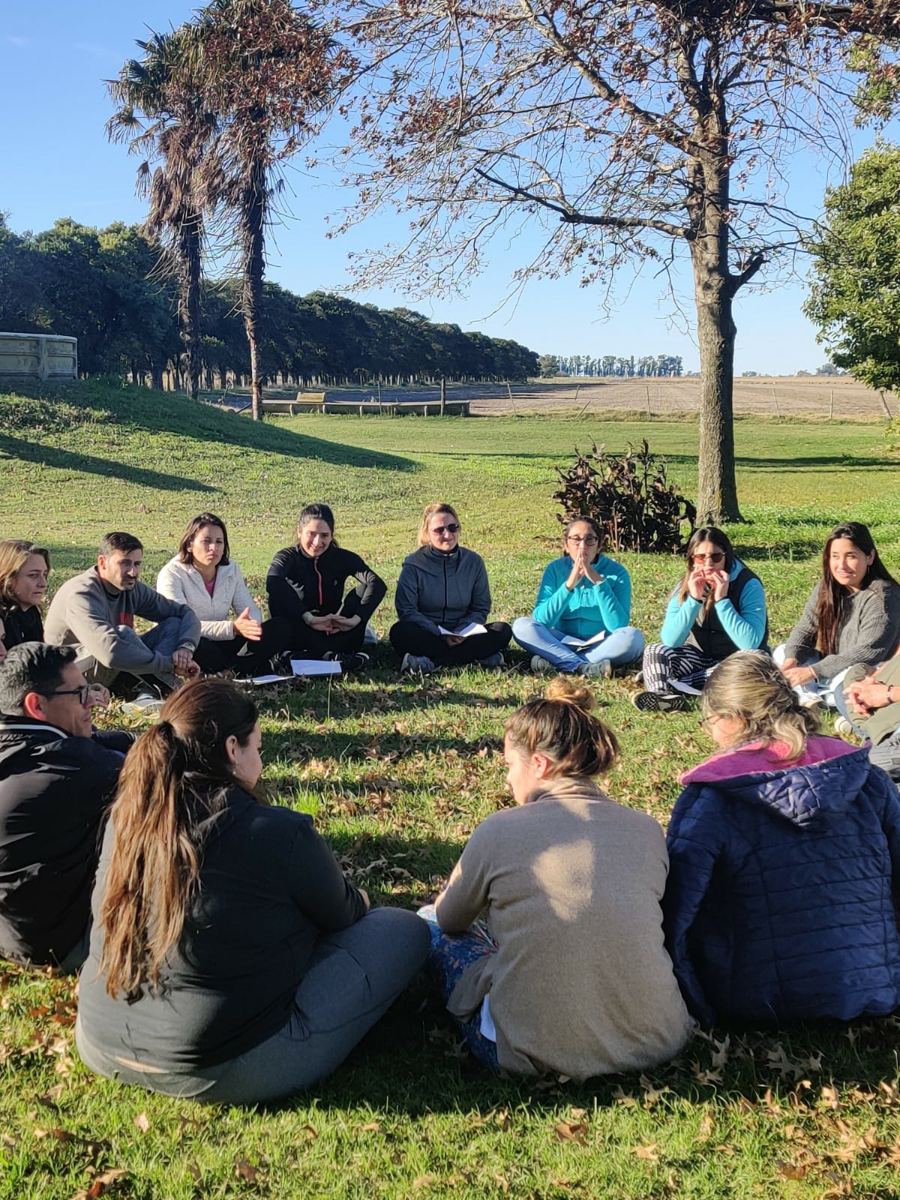 Estudiantes sentados en ronda al aire libre durante una actividad de la carrera
